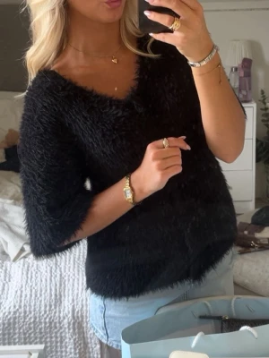Svart fluffig topp från Wera - Säljer en svart fluffig topp från Wera med v-ringning och halvlånga ärmar. Toppen har en mjuk och lurvig textur som ger en mysig känsla och passar perfekt till jeans eller kjol. Enkel men ändå trendig design.