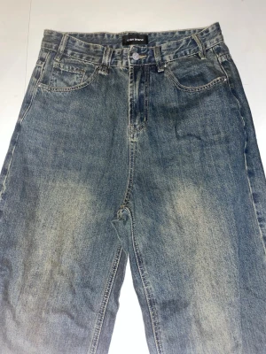 Blå jeans från 11kn brand - Ett par klassiska blå jeans från 11kn brand med fem fickor och knappgylf. Jeansen har en tvättad look med ljusare partier och baggy ben. Perfekta för en avslappnad stil och passar till det mesta i garderoben.