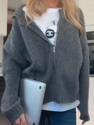 Grå ribbad zip-kofta - Mysig grå kofta med dragkedja framtill och ribbad struktur. Koftan har en avslappnad passform, långa ärmar och breda muddar. Perfekt att slänga över en t-shirt för en chill look.