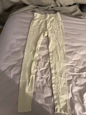 Ribbade beige leggings high waist - Säljer ett par ribbade leggings i beige med hög midja och stretchigt material. Perfekta för dig som gillar en enkel men trendig look. De har en smickrande passform och är superbekväma att bära hela dagen.