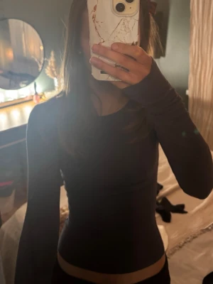 Mörkgrå långärmad topp - En enkel och stilren mörkgrå långärmad topp med rund hals. Tight passform som sitter snyggt på kroppen. Perfekt att matcha med jeans eller kjol för en clean look.