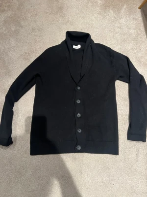 Svart kofta från Lindbergh - Hej! Jag säljer denna svarta Lindbergh cardigan/koftan. Den är i fint skick. Bara hör av dig om du har någon fråga. Säljer för 450kr men kan gå ner lite i pris.