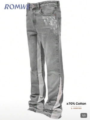 Flared jeans herr - Säljer ett par grå jeans från ROMWE med breda vita stripes längs benen. Jeansen har fem fickor, hög midja och raka ben med rå kant längst ner. Materialet består av minst 70% bomull och de har en cool, avslappnad vibe.