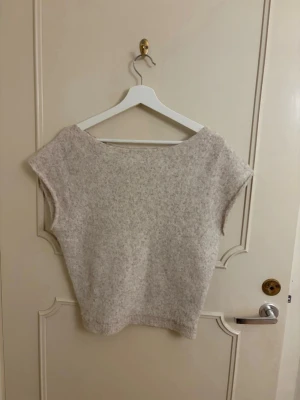 Beige stickad ärmlös tröja - Stickad från Nelly, ena sidan går ner som off shoulder, storlek S