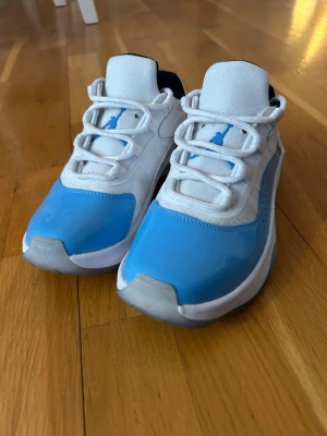 Vita och blå Air Jordan sneakers - Snygga sneakers från Air Jordan i vitt och ljusblått med klassisk Jumpman-logga på plösen. Skorna har vita snören, mesh- och syntetmaterial samt grå detaljer på hälen. Perfekta för dig som vill sticka ut med en sportig look. Funkar för både vardag och även basket. Hör av er vid frågor!🙌 Skicket är så gott som nytt✅