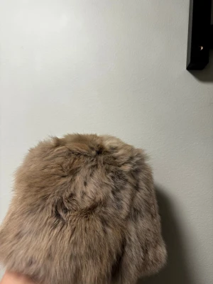 Beige pälsmössa i klassisk stil - Säljer en fluffig och varm pälsmössa i beige med naturliga bruna skiftningar. Mössan har en klassisk rund form.Perfekt för dig som vill ha en statement-accessoar till vintern.