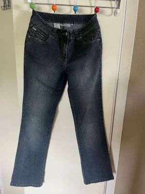 Mörkblå bootcut jeans - Snygga mörkblå bootcut jeans med klassisk femficksdesign och lätt slitning på låren. Jeansen har normal midja och raka ben som går ut lite nedtill. Tillverkade i denim med en skön känsla och passform. Perfekta för en avslappnad och trendig look.