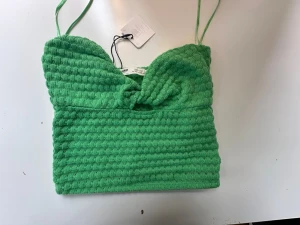 Grön ribbad linnetopp med knut - Trendig grön linnetopp med smala axelband och snygg knutdetalj framtill. Toppen är ribbad och har en croppad passform som passar perfekt till höga jeans eller kjol. Materialet känns mjukt och bekvämt mot huden.