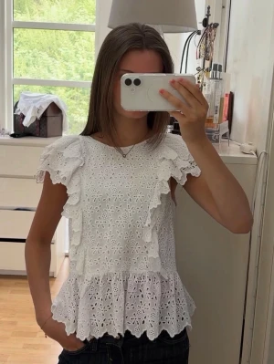 Vit topp med broderade volanger - Jättesnygg topp från H&M. Kommer tyvärr inte till användning längre!! Storlek Xs-S