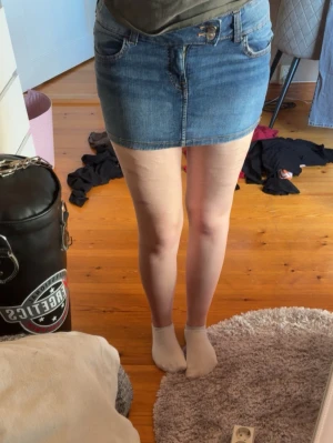 Blå jeanskjol i klassisk modell - Snygg blå jeanskjol med femficksdesign och knappgylf. Kort modell med rå kant nertill och klassiska jeanssömmar. Perfekt för dig som gillar en enkel och tidlös stil. Passar till allt och är lätt att matcha med olika toppar. Nästan aldrig använd. Storlek 38 men passar 36