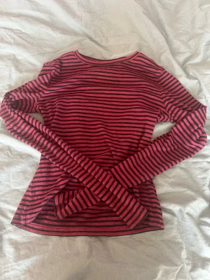 Randig långärmad tröja - Säljer en långärmad tröja från Lindex i storlek XS. Toppen är randig i rött och svart med rund halsringning och figurnära passform. Perfekt att styla med jeans eller kjol för en cool och avslappnad look. Har stretch så sitter åt runt kroppen för att ge en snygg figur🩷