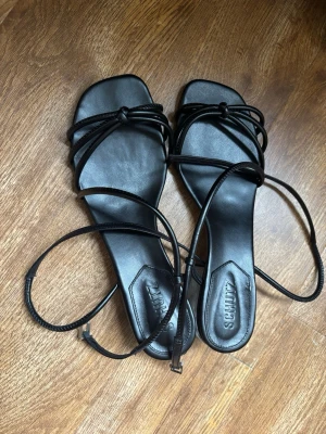 Svarta sandaletter från Schutz - Schutz svarta minimalistiska sandaletter med tunna remmar och modern transparent blockklack. Elegant och stilren design som passar perfekt till både fest, middag och sommarlooks. Bekväm låg klack och justerbar ankelrem för bra passform.  Fint begagnat skick med normala mindre bruksspår undertill. Tidlös modell som är lätt att matcha med både klänning, jeans och kostymbyxor.