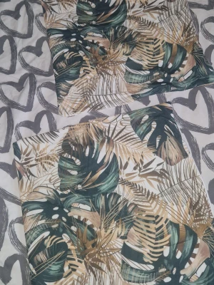 Kuddfodral 2st - Två kuddfodral med tropiskt bladmotiv i skönt material. Mönstret består av stora palm- och monstera-blad perfekt för att ge soffan eller sängen en fräsch och trendig känsla. Tillverkade i mjukt tygmaterial. Måtten är ca 44,5×43,5cm