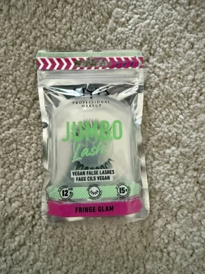 Jumbo Lash Fringe Glam ögonfransar - Jumbo Lash Fringe Glam är veganska ögonfransar från NYX Professional Makeup. Förpackningen är silverfärgad med rosa och gröna detaljer. Produkten är framtagen för att ge fylligare och längre fransar och är cruelty free.