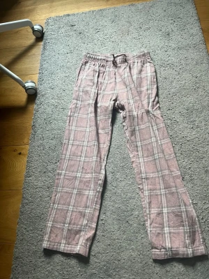 Rutiga rosa pyjamasbyxor - Mysiga pyjamasbyxor i rosa med vitt och grått rutmönster i strl 150, använda fåtal gånger men är i mycket bra skick!💕 