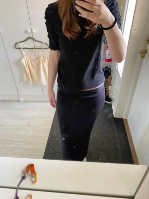 Svart topp med puffärmar - Snygg svart topp med puffade axlar och halvlånga ärmar. Materialet är ribbat och ger en cool struktur. Passformen är normal och toppen har en rund halsringning. Perfekt att styla med både jeans och kjol.
