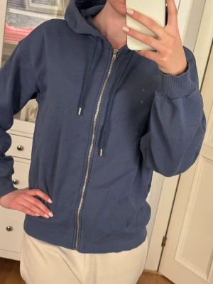 Blå zip-hoodie från Gina Tricot - Mysig blå hoodie från Gina Tricot med dragkedja framtill och justerbar huva med snören. Kan synas några små fläckar. 