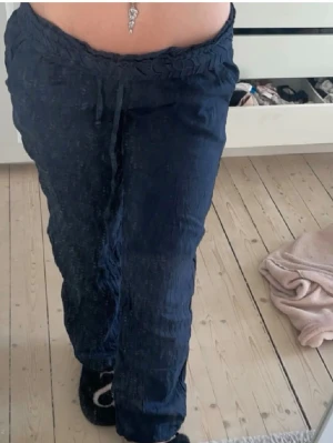 Mörkblå mjukisbyxor med dragsko - Säljer ett par mörkblå mjukisbyxor med avslappnad passform och bred resår i midjan samt dragsko. Byxorna har raka ben och är perfekta för en chill look. Materialet känns mjukt och bekvämt mot huden.