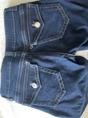 Mörkblå utsvängda jeans med ficklock - Mörkblå bootcut jeans från hm lowaist i storlek 32 knappt använda tyvärr för tajta på mig de är rätt långa jag är 162 å de går ner hela vägen å lite lite till