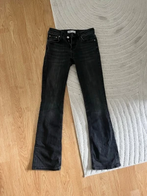 Svarta low waisted bootcut jeans från Zara - Säljer ett par svarta bootcut jeans från Zara, med låg midja i storlek 34. Jeansen är lite urtvättade men passar både till vardag och mer uppklätt.