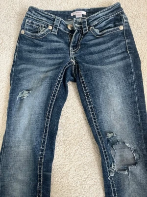 Blå bootcut jeans med broderade fickor och hål på knäna - Snygga blå bootcut hiphuge jeans från gina tricot med slitningar och hål på knäna. Bakfickorna har detaljerade broderier som ger extra stil. Jeansen har en klassisk tvättad look och är tillverkade i denim. Perfekta för dig som gillar en avslappnad och trendig stil. Jensen är slutsolda i butik! De är lite slitna i byxbuntarna på baksidan men syns inte frammifrån!💕
