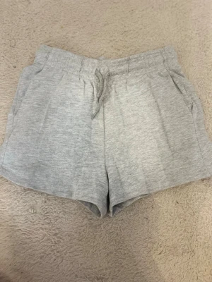 Gråa mjukis shorts  - Ett par ljusgrå shorts i mjukt bomullsmaterial och snörning framtill. Shortsen har en avslappnad passform och två fickor på sidorna. 