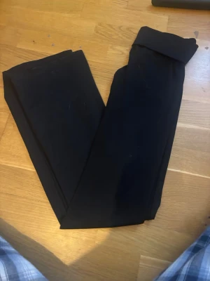 Svarta bootcut leggings i tränings material  - Säljer ett par svarta leggings med bootcut-modell. De har låg  midja och en kant som man antingen viker ner eller har högmidjade , och är tillverkade i ett stretchigt material som sitter skönt på kroppen. Perfekta till både chill och snygga outfits, även att träna i.