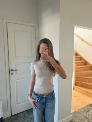 Topp med krage - Snygg beige polotopp med korta ärmar och ribbade kanter. Toppen har en tight passform och är gjord i mjuk bomull, perfekt att styla med jeans eller kjol. Enkel och stilren design som passar till många looks. Säljer denna då den inte kommer till användning längre💕priset kan diskuteras🥹