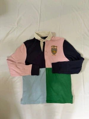 Ralph lauren tröja - Polo Ralph Lauren Rugbytröja – Flerfärgad Patchwork – Strl M Säljer en snygg och klassisk rugbytröja från Polo Ralph Lauren i patchwork-design med färgblock i marinblått, rosa, grönt och ljusblått. Tröjan har broderad crest-logga framtill och stort nummer “9” på ryggen. Kraftig bomullskvalitet med vit krage och klassisk rugby-passform. Märke: Polo Ralph Lauren Storlek: M Modell: Custom Fit Färg: Flerfärgad / patchwork Skick: Bra använt skick, normal användning utan större skador