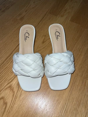 Vita flätade pumps / klackar från Clou - Snygga vita pumps från Clou med flätad rem och låg klack. Använda enstaka gång.
