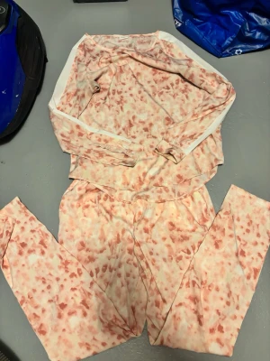 Rosa och vit tie-dye loungewear set Jaqueline de Yong - Mysigt loungewear set med långärmad tröja och byxor i mjukt material. Setet har ett rosa och vitt tie-dye mönster och elastisk midja på byxorna. Perfekt för chill dagar men ändå sticka ut.