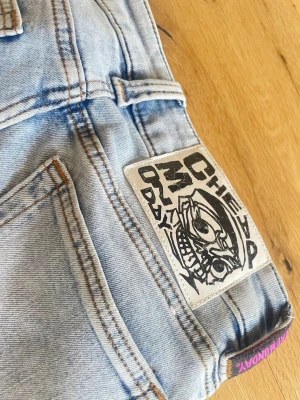 Ljusblå bootcut jeans från Cheap Monday - Säljer ett par ljusblå bootcut jeans från Cheap Monday med klassisk femficksdesign och ikonisk logga bak i storlek 25/32. Jeansen har en lätt tvättad look och lila Cheap Monday-detalj vid linningen.  