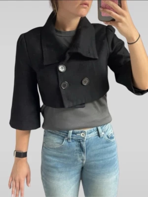 Kort svart kavaj från Gestuz - Snygg svart kort kavaj från Gestuz med dubbelknäppning och bred krage. Modellen har trekvartsärmar och en croppad passform som ger en cool och modern look. Perfekt att styla över en t-shirt eller klänning för en trendig outfit.
