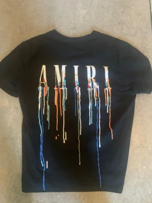 Svart AMIRI t-shirt  - Säljer en svart t-shirt från AMIRI med coolt tryck framtill och stort AMIRI-tryck på ryggen. Den passar både S/M