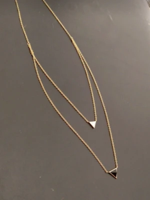 Guldigt halsband med trianglar - Snyggt dubbellager halsband i guld med två tunna kedjor och små minimalistiska trianglar som hängen. Perfekt för dig som gillar stilrena och trendiga accessoarer med geometriska former ifrån märket daily elegance