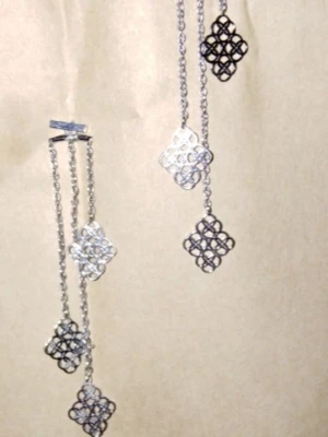 Långa örhängen med geometriska hängen - Säljer ett par långa örhängen i silver- och svartfärgad metall med flera geometriska, fyrkantiga hängen i ett öppet mönster. Kedjorna ger en cool och trendig look. Perfekta för dig som gillar unika accessoarer med modern känsla.
