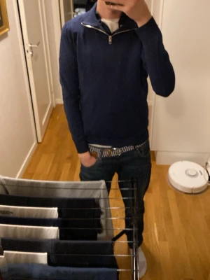 Mörkblå tröja med half zip från Jack and Jones - Mörkblå långärmad tröja med half zip-dragkedja vid halsen. Tröjan har en klassisk passform och är perfekt för lager-på-lager. Enkel och stilren design som funkar till det mesta.