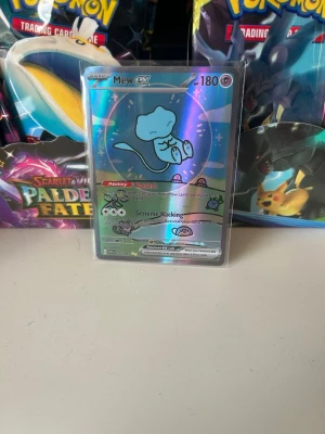 Pokémonkort Mew ex holo - Säljer ett Pokémonkort med Mew ex från Scarlet & Violet-serien. Kortet är holofoil med skimrande yta och har 180 HP. Motivet visar Mew i blått mot en glittrig bakgrund. Perfekt för samlare eller Pokémonfans! Kom med bud eller funderingar 
