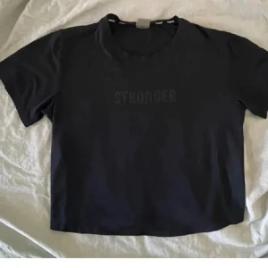 Tränings topp - Säljer svart tränings t-shirt från Stronger med svart tryck på bröstet. Använd fåtal gånger och därefter tvättad. Men fortfarande jättefint skick. Storlekslappens färg är lite avskaft men strl xs. Tror tröjan gått ut ur sortimentet då jag inte hittar den på hemsidan. Köparen betalar frakten!
