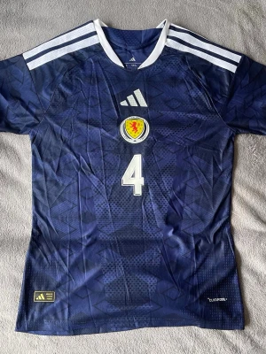 Scotland McTominay #4 - Riktigt clean Scotland-tröja med McTominay #4 på ryggen 🔥 Mörkblå design med feta detaljer och snyggt mönster i tyget.  • Scotland landslag • Scott McTominay #4 • storlek M (L passar som M) • ClimaCool • Sjukt snygg färg och passform • Perfekt till både vardag och fotboll  En ovanligare tröja man inte ser så ofta 👌  💰 Pris: 400 kr 📍 Kan mötas / skickas  