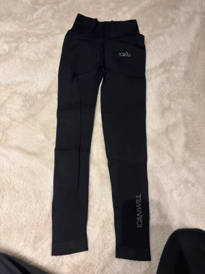 Svarta leggings från ICANIWILL - Snygga svarta leggings från ICANIWILL med hög midja och scrunch-detalj bak. Tight passform och stretchigt material som passar perfekt till träning eller chill. Logga på benet och vid höften. Riktigt bekväma och stilrena.