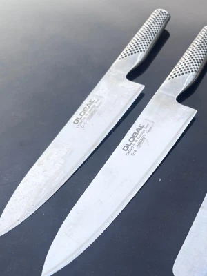 Global kockknivar i rostfritt stål G-2 - Två stilrena kockknivar från Global i rostfritt stål. Knivarna har ett klassiskt mönstrat handtag för bra grepp och är perfekta för matlagning. Båda har en elegant, silverfärgad finish och är designade för precision och balans.