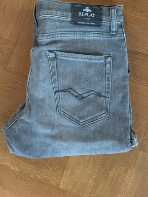 Grå raka jeans från Replay - Snygga grå jeans från Replay med raka ben och klassisk femficksdesign. Jeansen har en diskret tvättad look och bakficka med unik söm. Perfekta till en avslappnad streetstyle eller casual outfit.