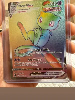 Pokémonkort Mew VMAX Fusion Strike - Pokémonkort Mew VMAX Fusion Strike med holografisk yta. Kortet har en färgglad design med Mew i grönt, blått och rosa. Kortet är inplastat i ett skyddsfodral och har attackerna Cross Fusion Strike och Max Miracle. Perfekt för samlare eller Pokémonfans.