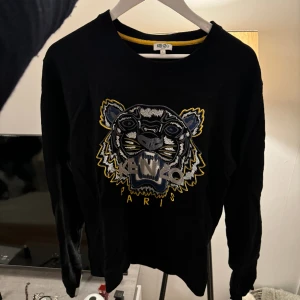 KENZO Tröja - Tröja från KENZO. Broderad. Storlek L men passar som M (KENZO har väldigt små storlekar!) Köpt 2018 då jag använde den väl (som ni kan se på tvättlappen).  Efter dess har den bara hängt i garderoben. Tyvärr ingen förpackning kvar. Bra pris! 💸