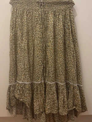 Leopardmönstrad volangkjol - Säljer en snygg leopardmönstrad kjol med volangkant och smock i midjan. Kjolen är i ett lätt och luftigt material, perfekt för dig som gillar djurmönster och vill ha en trendig look.