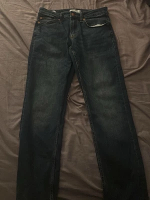 Mörkblå jeans från Only & Sons - Snygga mörkblå jeans från Only & Sons med klassisk femficksdesign och raka ben. Jeansen har en diskret tvättad look och läderpatch med logga bak i midjan. Perfekta för en avslappnad och trendig stil.