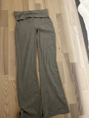 Grå utsvängda leggings - Grå leggings med utsvängda ben och bred, vikt linning. Mjukt och stretchigt material som sitter skönt på kroppen. Perfekta för en avslappnad och trendig look. 