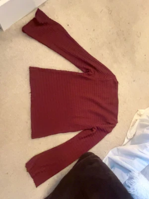 Vinröd långärmad topp från 157 - Mysig vinröd långärmad topp från 157 med våfflad struktur. Tröjan har en enkel, rak passform och är tillverkad i ett mjukt material som känns skönt mot huden. Perfekt att styla med jeans eller kjol för en avslappnad look.