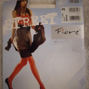 HELT NYA OANVÄNDA vita microfibertights / strumpbyxor / tights från Fiore, XS-S  - HELT NYA OANVÄNDA vita, semi-opaque microfibertights från Fiore, modell Street, XS-S. Tightsen är släta och har en mjuk känsla tack vare materialblandningen med 85% polyamid, 13% elastan och 2% bomull. Perfekt för dig som vill ha en clean och stilren look till tex kjol eller klänning. Felfria. Skyltdockan visar ungefär hur de ser ut på.